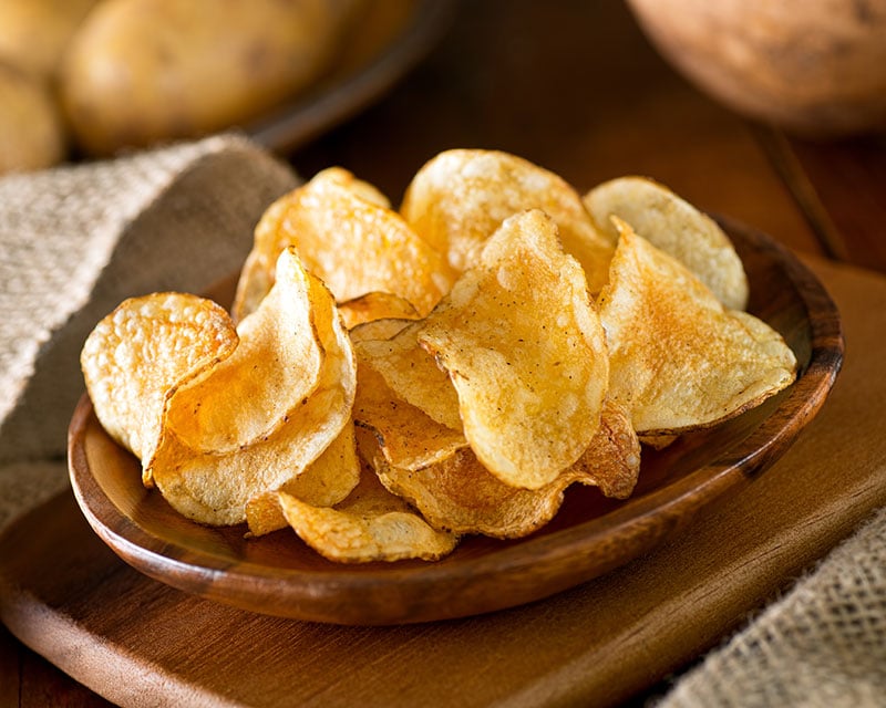 A wooden bowl full of crisps