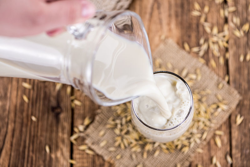Pouring oat based milk into jug