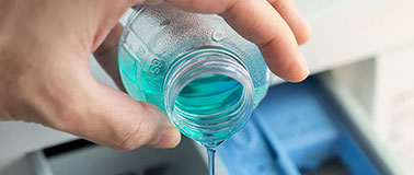 Man pouring concentrated liquid detergent into a machine