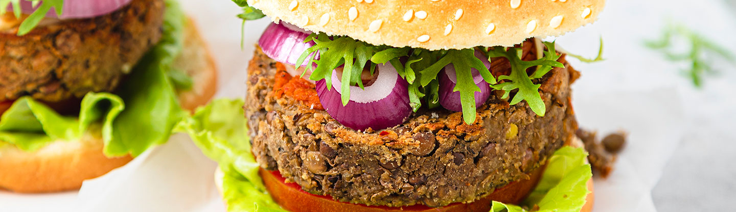 A plant-based burger in a bun with salad