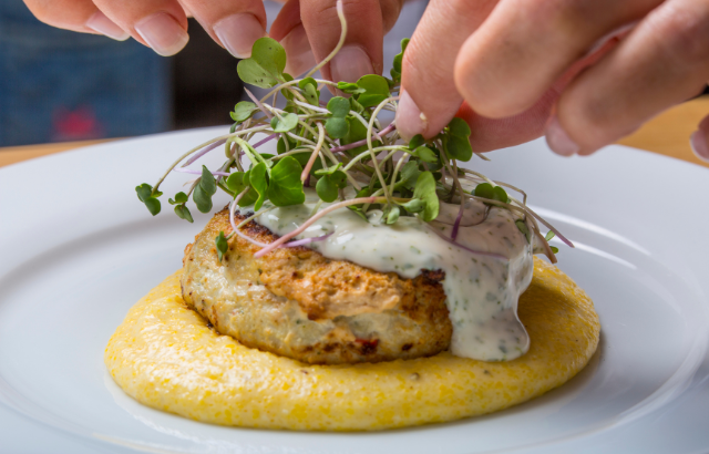 plated dish with microgreens being applied on the top