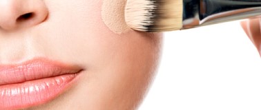 Woman applying coverage makeup with an applicator brush