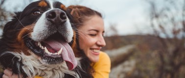 smiling woman hugging a happy dog outdoors
