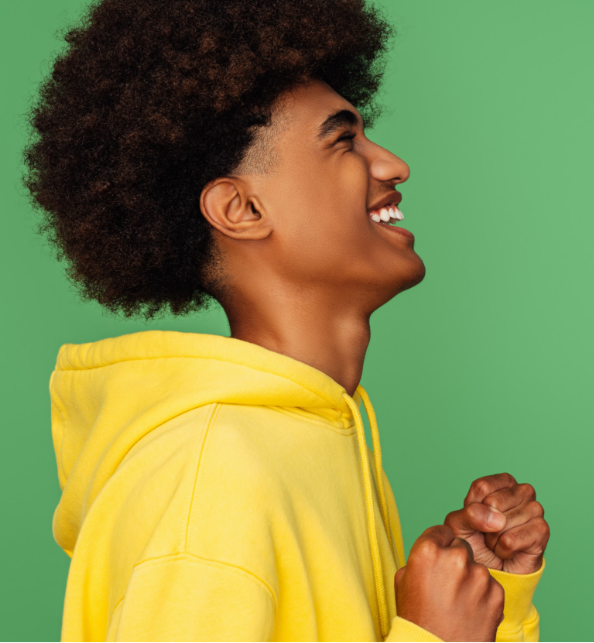 Man wearing a bright yellow hoodie laughing in front of a green background
