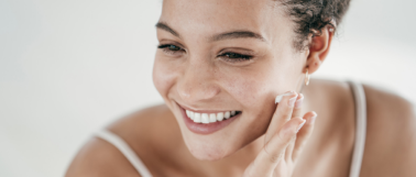 A hair woman applies plant-based moisturizer to her freshly cleansed face